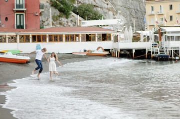 A young couple walks along the beach, in the port of Sorrento.