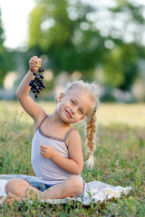 cute little girl eating grapes in the park
