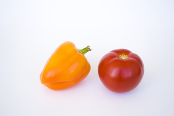 Yellow orange pepper and tomato isolated on white background is used as decoration element.