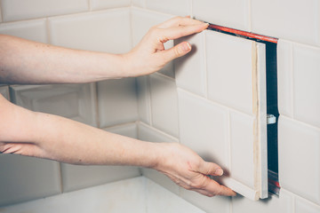 The girl opens a hidden hatch on the wall of the tile to access the inspection hole of the sewer pipe to eliminate clogging and cleaning