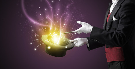 Magician hand conjure with wand  light from a black cylinder