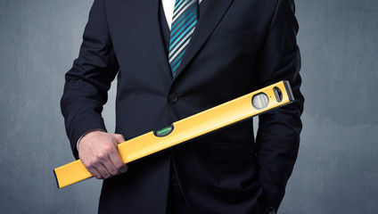Young, handsome, cute businessman holding tool with grey background