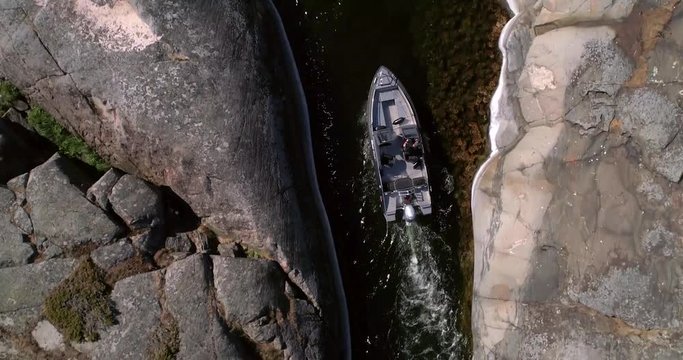 Boat in the archipelago, C4K aerial top down view following a boat inside a rocky island, on a sunny summer day, in saaristomeri national park, Varsinais-suomi, Finland