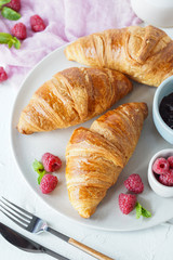 Breakfast with croissants, tea, confiture and berries on white background