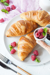 Breakfast with croissants, tea, confiture and berries on white background