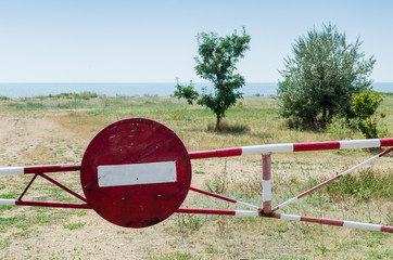 Barrier with a road sign blocks the road and prohibits passage to the sea