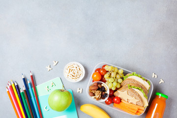 Back to school concept. Healthy lunch box and colorful stationery on gray stone table top view.