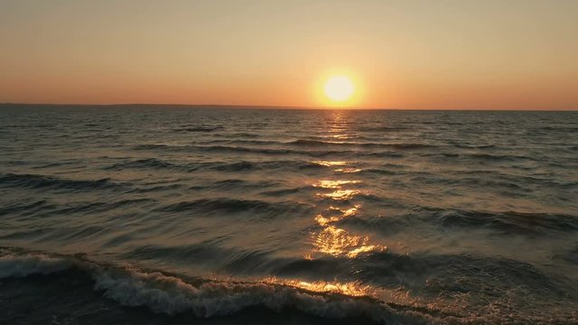 Aerial drone footage of sea waves moving towards shore. Beautiful view of seascape during sunset. 4K Resolution.

