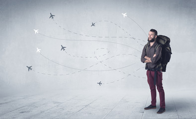 Handsome young man standing with a backpack on his back and little planes in the background