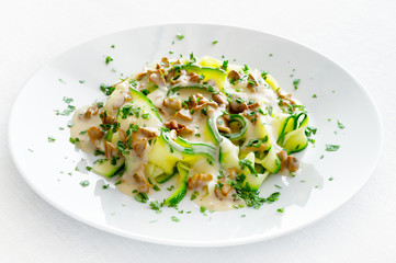 vegetable pasta under white sauce with chanterellas sprinkled with parsley