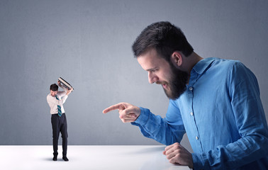 Young professional businessman being angry with an other miniature businessman in front of a...