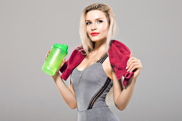 Charming model posing in the studio with a shaker in her hands and a towel around her neck