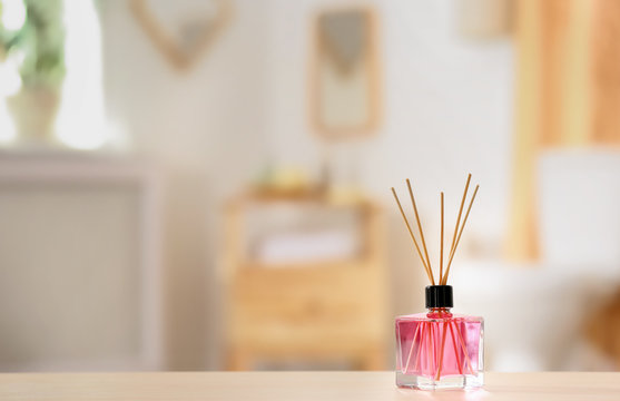 Aromatic reed air freshener on table against blurred background