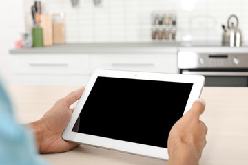 Man with modern tablet at table indoors, closeup