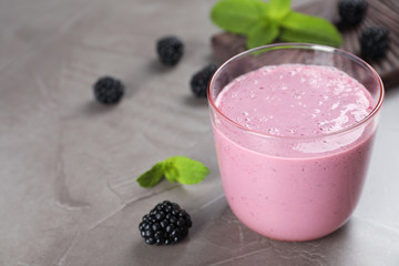 Glass with blackberry yogurt smoothie on grey table