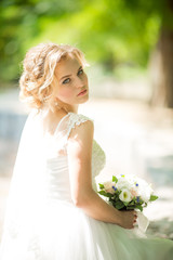 Beautiful blonde bride with stylish make-up in white dress with a wedding bouquet