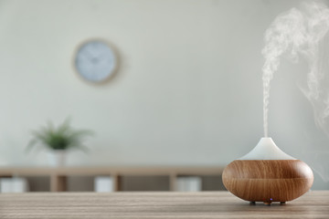 Modern aroma lamp on table against blurred background with space for text