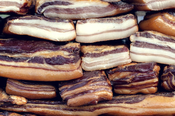 Stack of smoked bacon as a background. Regional, traditional and healthy meat products at the fair.