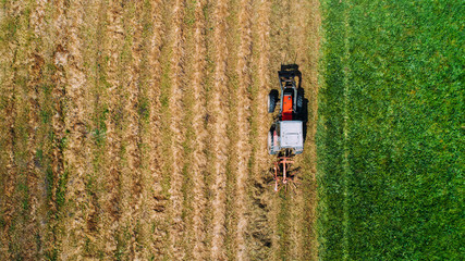combine harvester - aerial view, drone view of modern combine tractor on the golden hay field in the summer. Rotary rakes with tractor