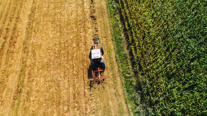 harvester using tractor with rotary rakes for collecting hay. Aerial drone view, agricultural details