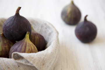 Fototapeta premium Fresh figs in a bowl on a white wooden table, side view. Close-up.
