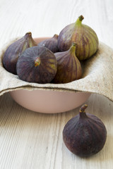 Fresh figs in a pink bowl on a white wooden background, side view. Close-up.