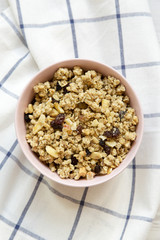 Pink bowl of fruit granola on cloth, overhead view. Close-up.