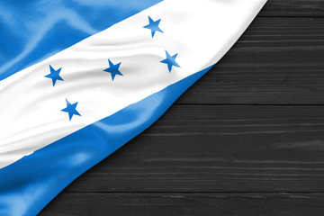 Flag of Honduras and place for text on a dark wooden background - obrazy, fototapety, plakaty
