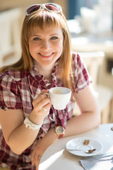 A young girl sitting in a cafe with a Cup of coffee.