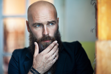 Portrait of bearded thoughtful man strokes beard