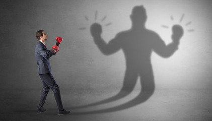 Fototapeta premium Businessman trying to fight with his unarmed shadow 