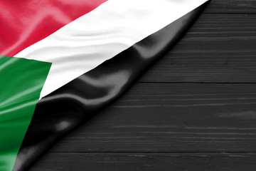 Flag of Sudan and place for text on a dark wooden background