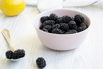 Ingredients for blackberries jam on a white wooden background, side view.