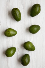 Whole avocados on white wooden background, top view. Overhead, from above.