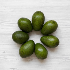 Whole avocados on white wooden surface, overhead view. Flat lay, from above, top view.