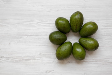 Whole avocados on white wooden surface, view from above. Flat lay, top view. Copy space.