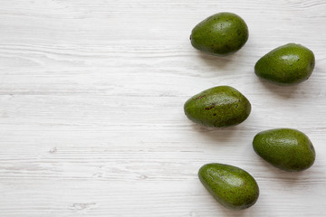 Whole avocados on white wooden surface, top view. Flat lay, overhead, from above. Copy space.