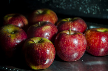 Muchas manzanas rojas en bandeja plateada con iluminación selectiva 