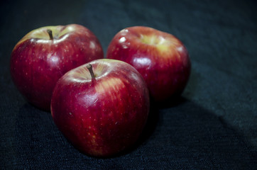 Tres manzanas rojas sobre un mantel negro