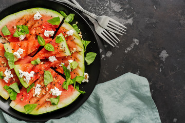 Grilled watermelon with cheese, basil and nuts on a concrete dark background. Top view, overhead, flat lay.