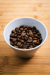 Cup of Coffee Beans roasted on a wooden table with fresh bean with great aroma