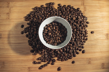 Fototapeta na wymiar Cup of Coffee Beans roasted on a wooden table with fresh bean with great aroma