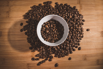 Cup of Coffee Beans roasted on a wooden table with fresh bean with great aroma