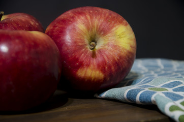 Manzanas rojas sobre tabla de madera con repasador con motivos verdes