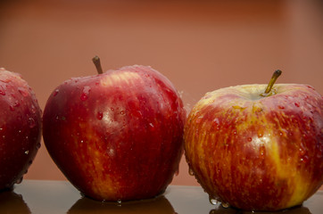 Tres manzanas mojadas sobre fondo rojo