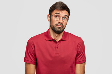 Lack of confidence. Awkward handsome man has clueless expression, feels doubt, shruggs shoulders...