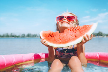 Little girl in pink sunglasses with bid watermelon segment funny portrait