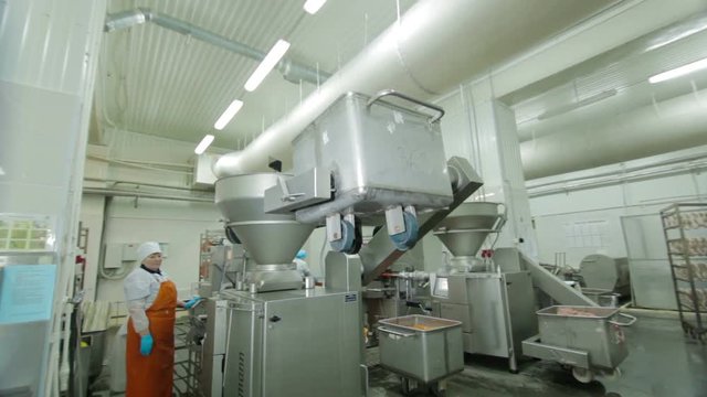 Worker produces sausages on automated food production equipment