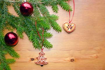 Christmas and New Year composition on a wooden background. A branch of a Christmas tree with an electric garland and Christmas decorations. Concept for a greeting card, poster. Place to insert text.