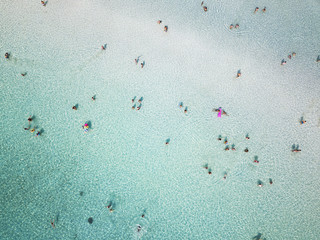Aerial view of relaxed people swimming on a clear  and transparent sea. Cala Brandinchi, Sardinia, Italy.